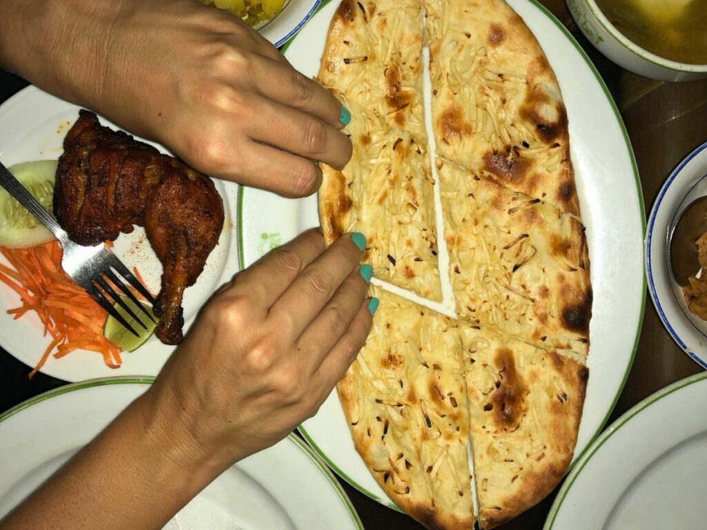 hands tearing naan bread bangladesh